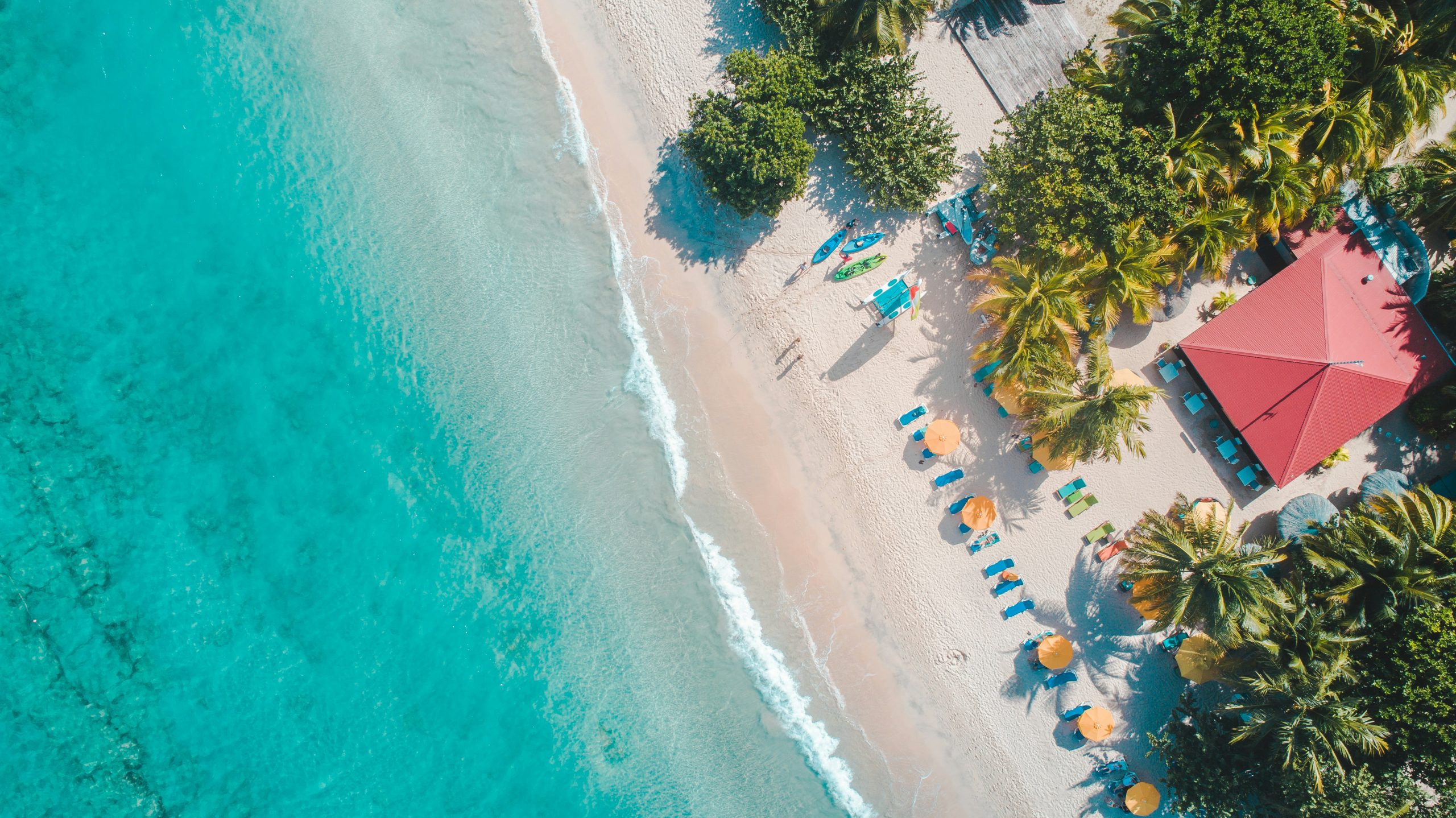 Famille (parents et enfants) jouant sur une plage de sable blanc et eau turquoise aux Antilles (Guadeloupe ou Martinique), parfaites pour des vacances famille Antilles.